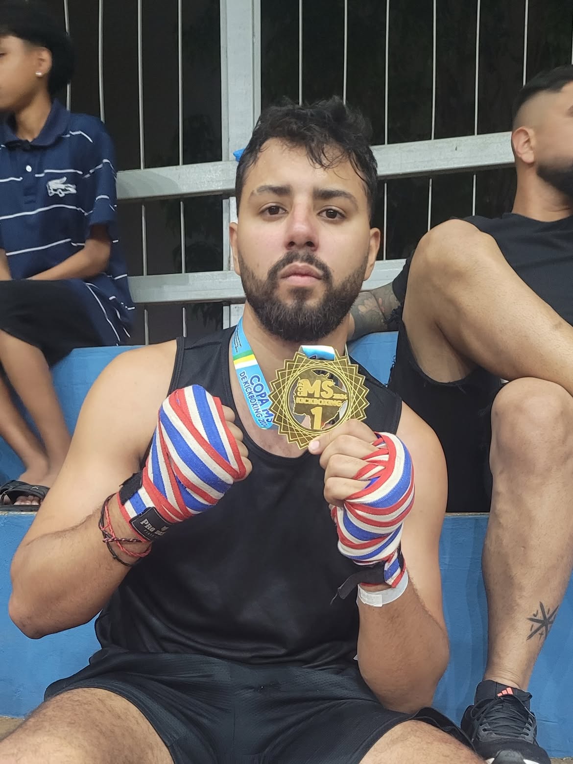 Atleta de kickboxing sentado com medalha e bandagens nas mãos