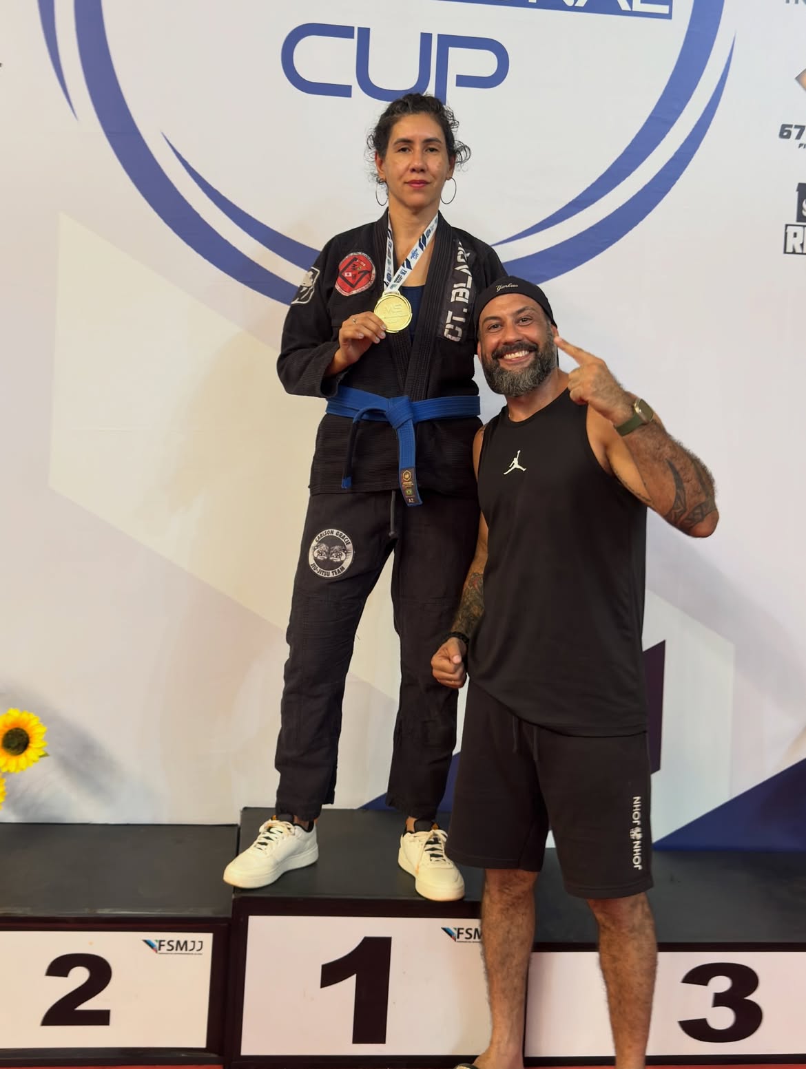 Atleta de kimono preto e professor no pódio com medalha