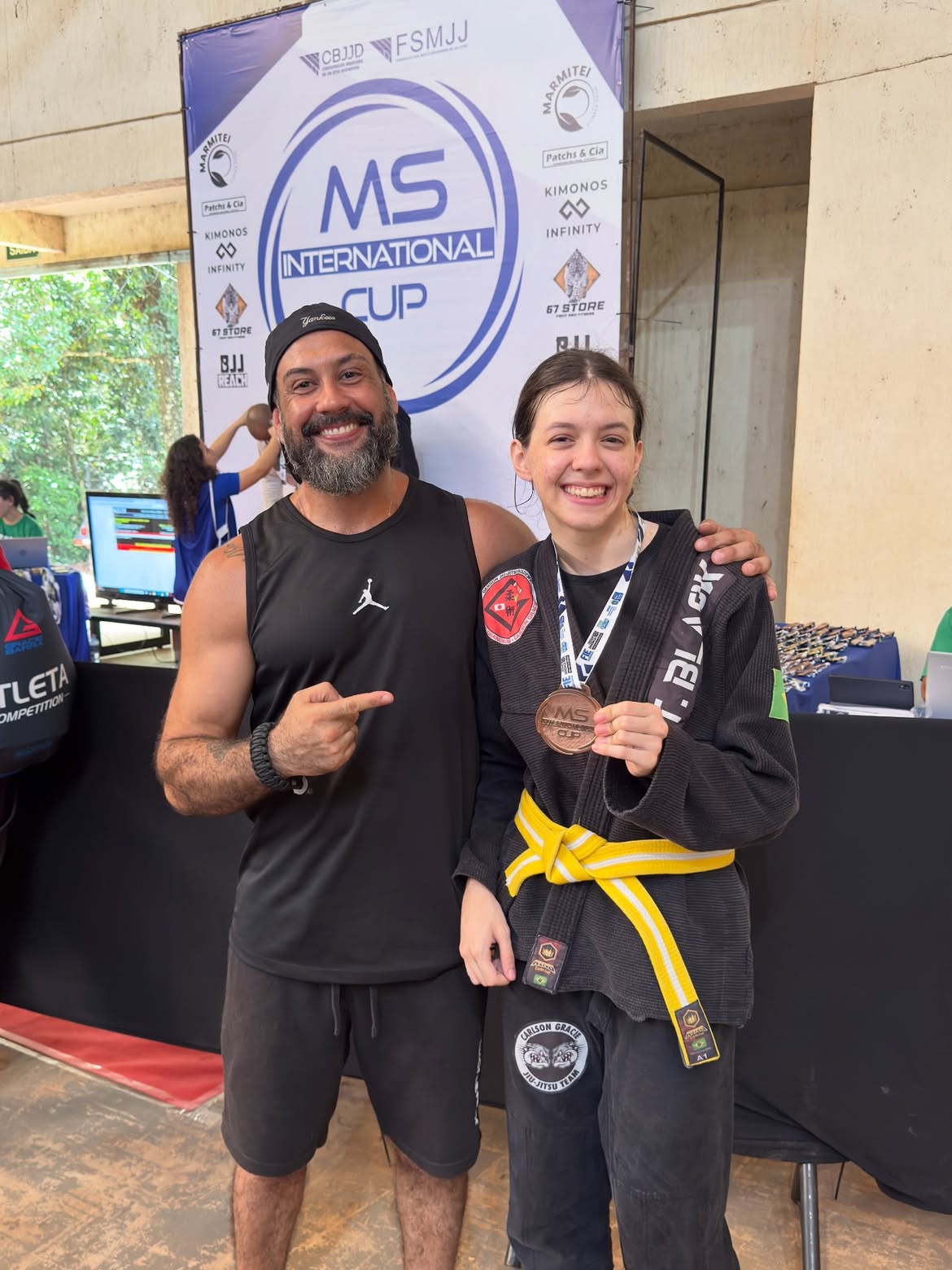Professor com jovem atleta de faixa amarela e medalha