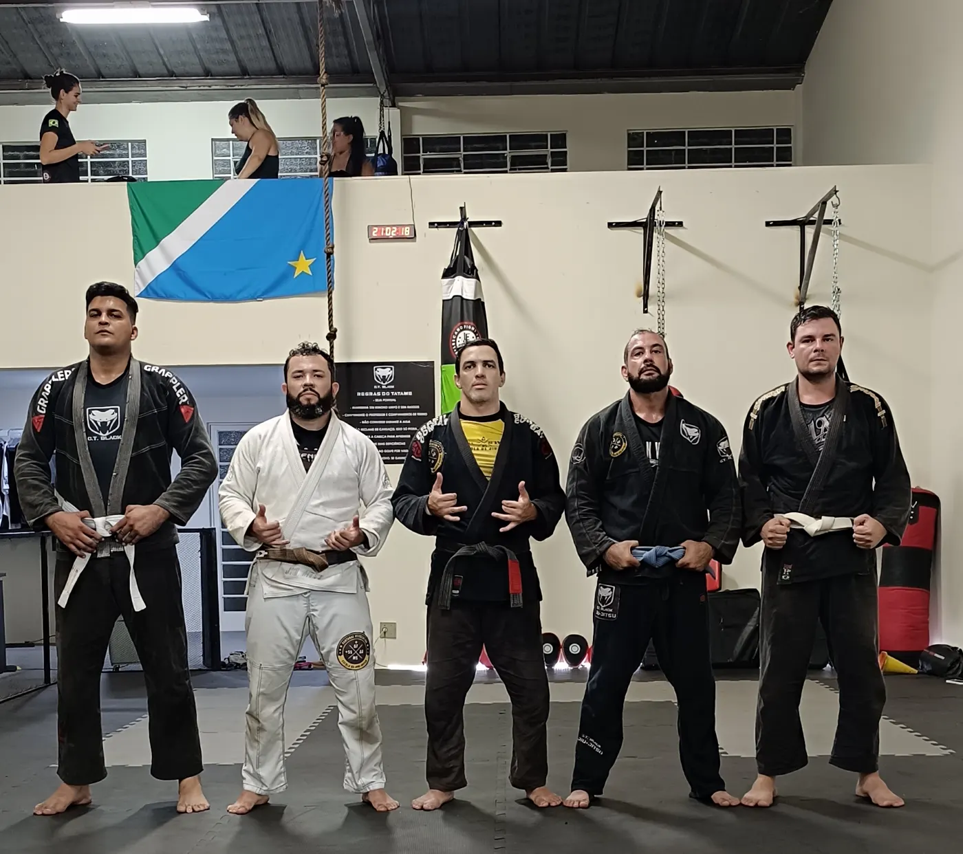 Equipe do CT Black Viper com kimonos pretos e brancos em frente à parede de sacos de pancada